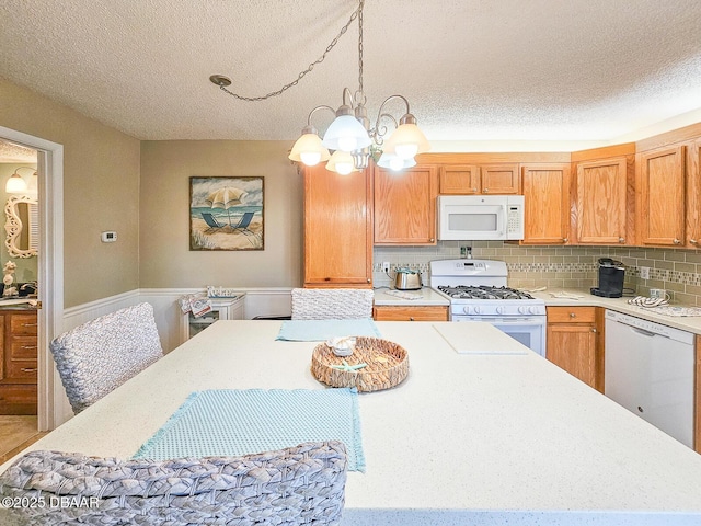 kitchen featuring a notable chandelier, light countertops, backsplash, a textured ceiling, and white appliances