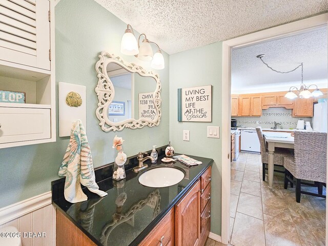 bathroom with tasteful backsplash, a wainscoted wall, a textured ceiling, vanity, and a chandelier