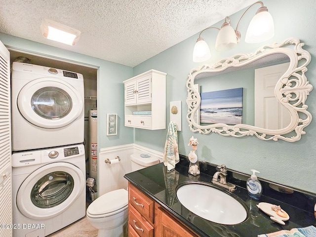 bathroom with stacked washer and clothes dryer, water heater, toilet, a textured ceiling, and vanity