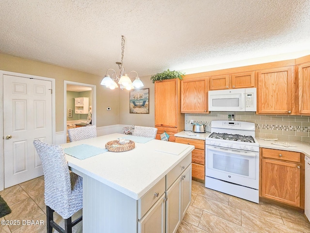 kitchen featuring white appliances, a breakfast bar, a kitchen island, light countertops, and backsplash