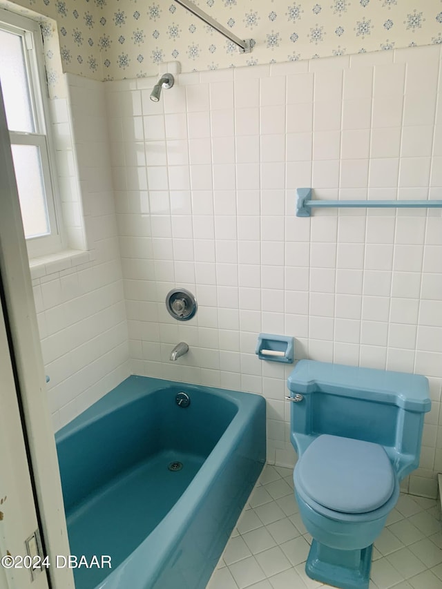 bathroom with wallpapered walls, bathtub / shower combination, tile patterned floors, toilet, and tile walls
