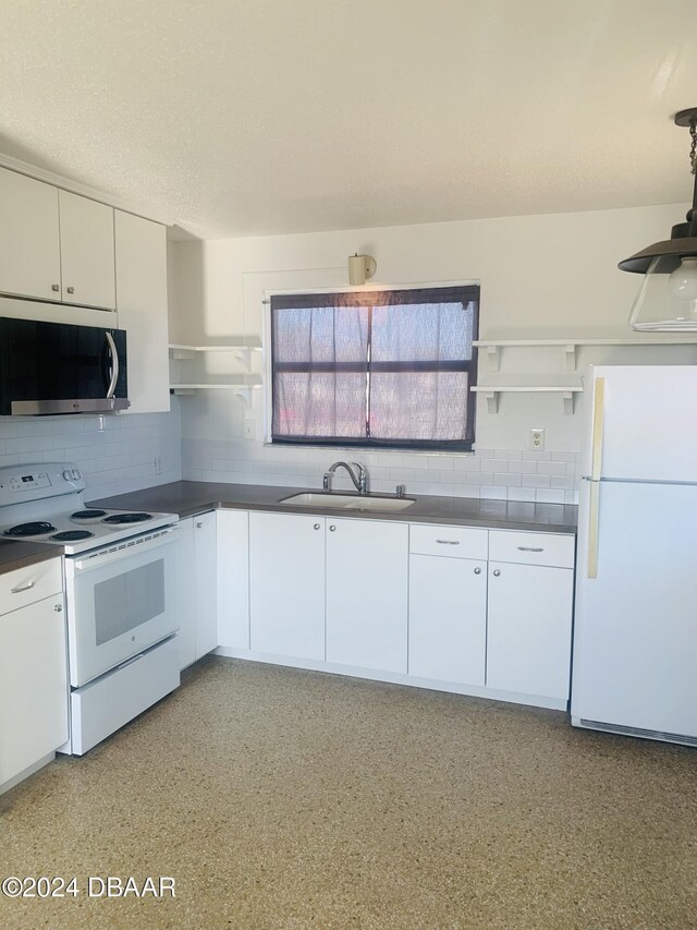 kitchen with white appliances, dark countertops, open shelves, and a sink