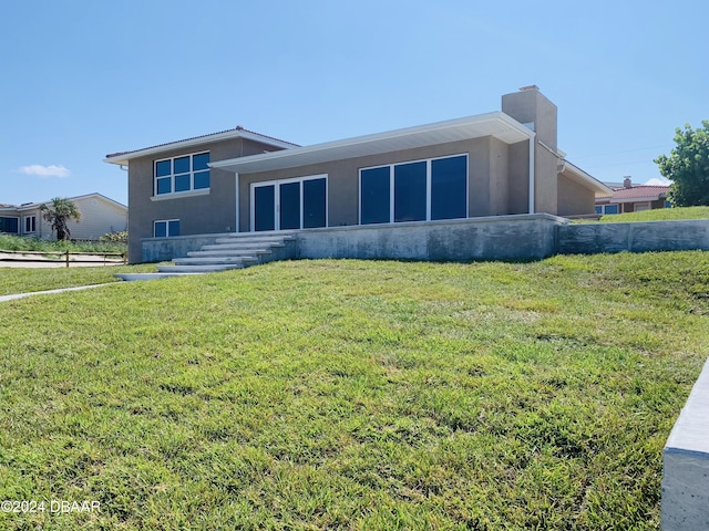 back of house with a yard, a chimney, and stucco siding