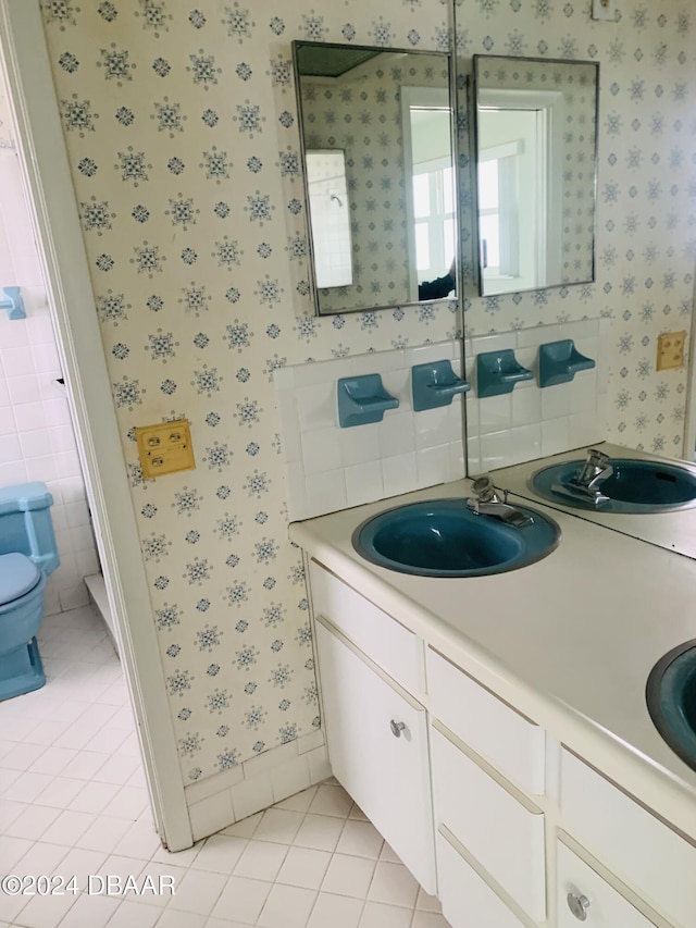 full bath featuring tile patterned flooring, toilet, wallpapered walls, and a sink