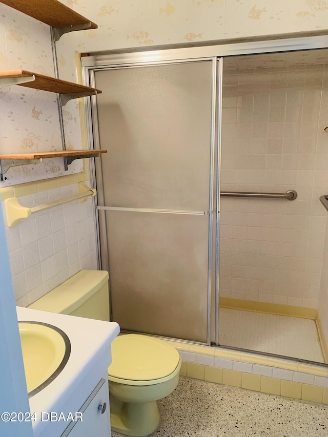 full bathroom with a shower stall, vanity, wallpapered walls, and speckled floor