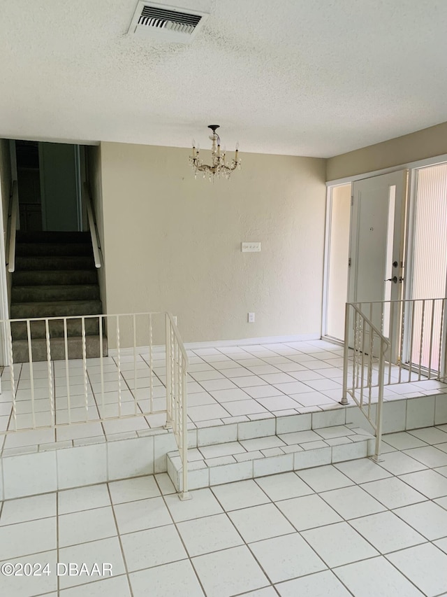unfurnished room featuring visible vents, a notable chandelier, stairs, and tile patterned flooring