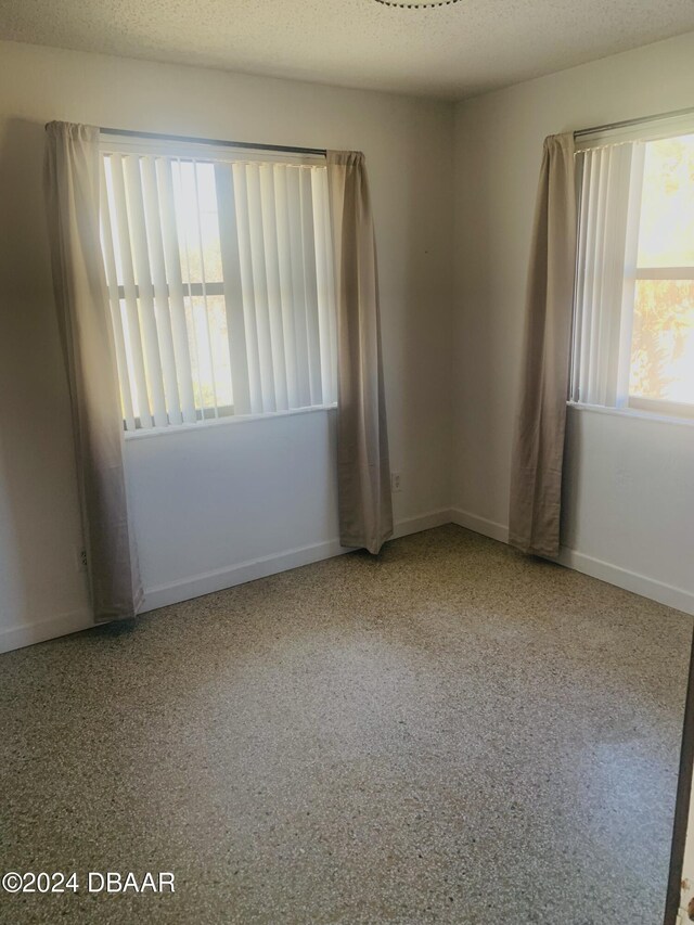 empty room with speckled floor, baseboards, and a textured ceiling