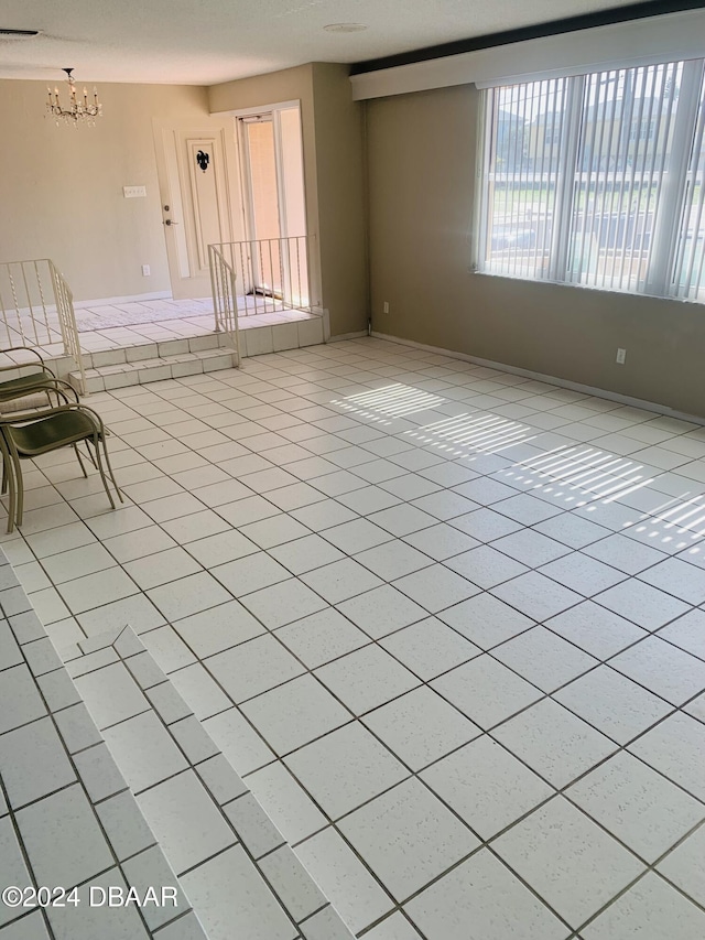 empty room featuring a notable chandelier, visible vents, and light tile patterned floors