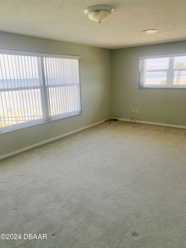 unfurnished room with carpet, baseboards, and a textured ceiling