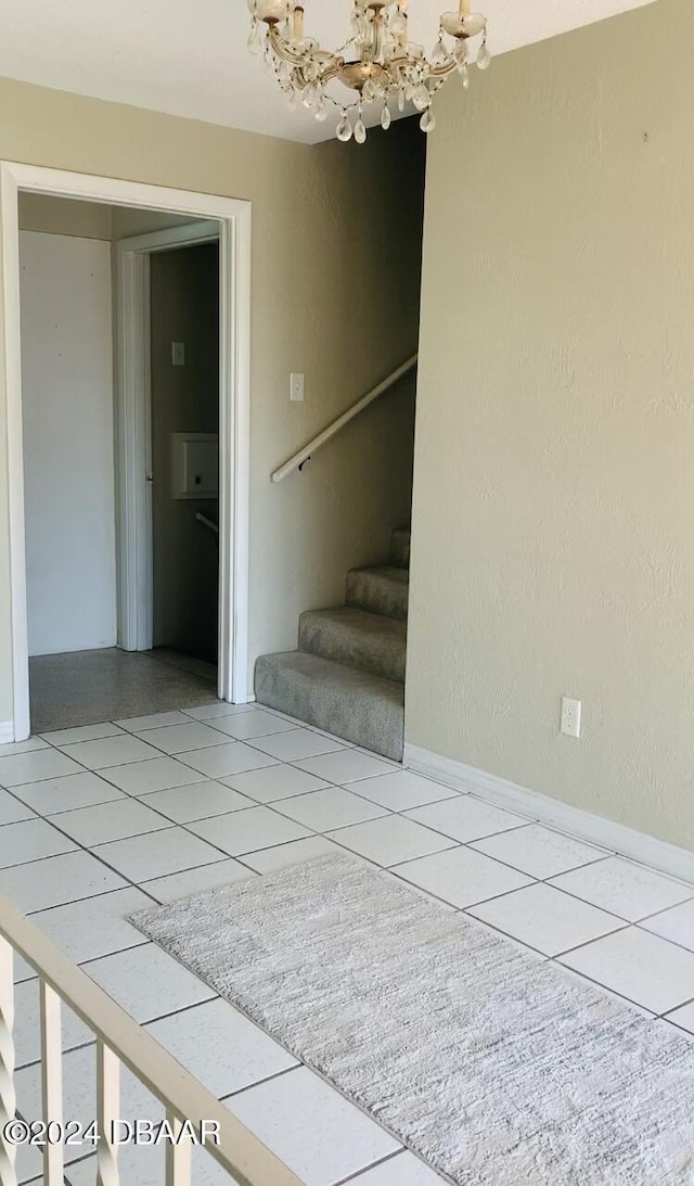staircase with baseboards, a chandelier, and tile patterned flooring
