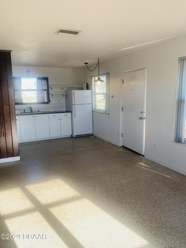 garage with visible vents, baseboards, freestanding refrigerator, and a sink