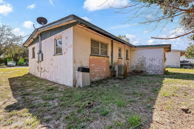 view of side of home with central AC and a lawn