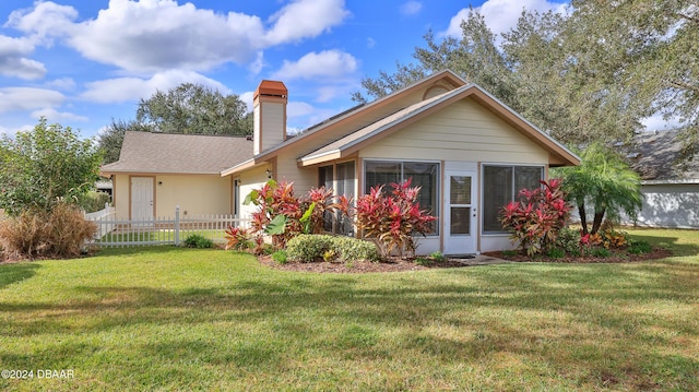 back of property with a garage, a shingled roof, a lawn, a chimney, and fence