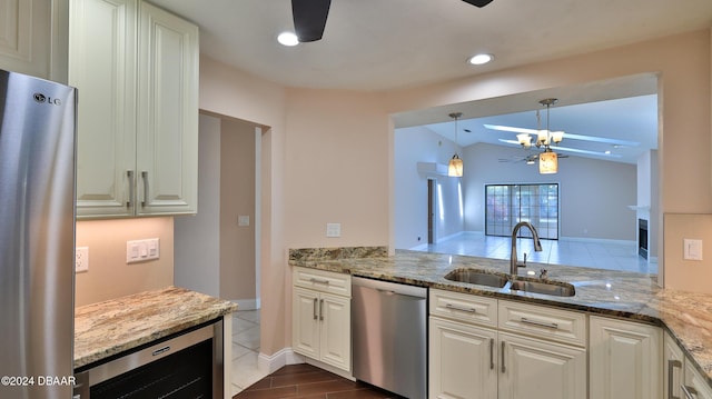 kitchen featuring beverage cooler, light stone counters, stainless steel appliances, pendant lighting, and a sink