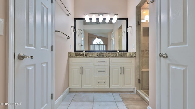 bathroom featuring double vanity, a sink, a shower stall, and tile patterned floors