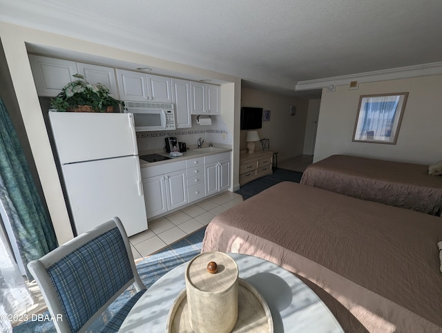 bedroom with light tile patterned floors, a textured ceiling, sink, and white refrigerator