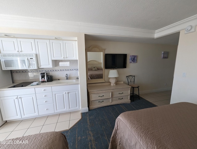 bedroom featuring a textured ceiling, sink, and light tile patterned floors