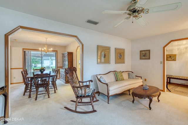 carpeted living room with ceiling fan with notable chandelier