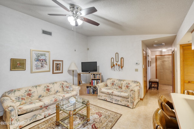 living room with vaulted ceiling, ceiling fan, and a textured ceiling