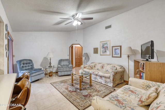 living room featuring lofted ceiling, a textured ceiling, ceiling fan, and light tile patterned floors