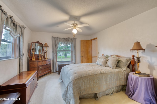 bedroom featuring a textured ceiling, light colored carpet, and ceiling fan