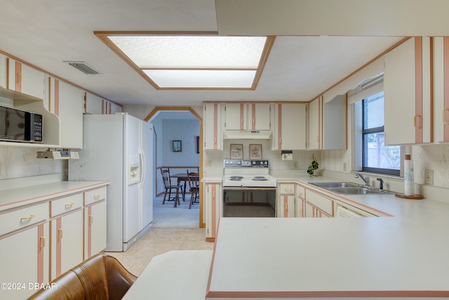 kitchen with light tile patterned flooring, sink, tasteful backsplash, white appliances, and white cabinets