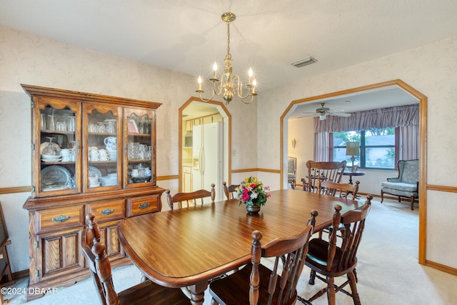 carpeted dining area featuring ceiling fan with notable chandelier