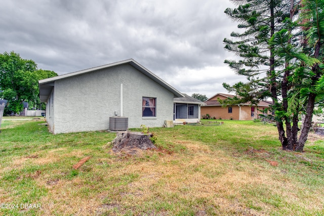 back of house featuring a lawn and cooling unit