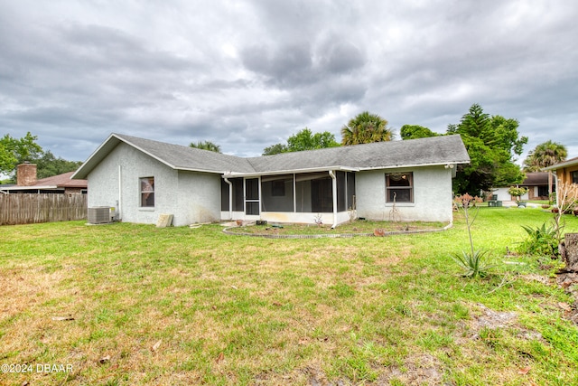 rear view of property featuring central air condition unit, a sunroom, and a yard