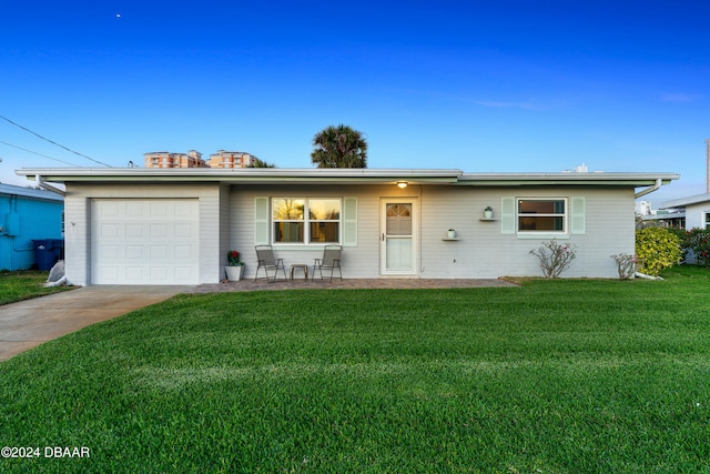 ranch-style home featuring a front yard, a garage, and a patio area