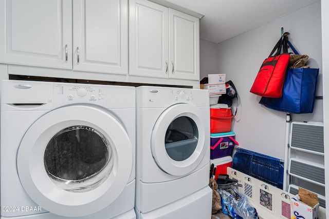 laundry area with cabinets, washer and clothes dryer, and a textured ceiling