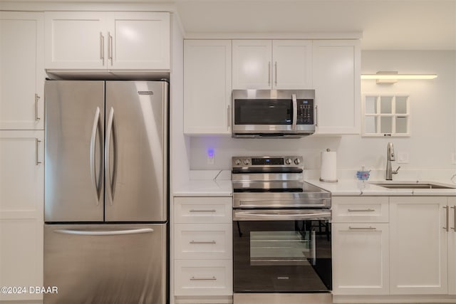 kitchen with stainless steel appliances, white cabinetry, and sink