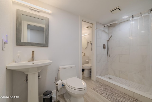 bathroom with a tile shower, hardwood / wood-style floors, and toilet