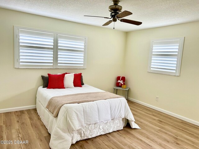 unfurnished room with a textured ceiling, light hardwood / wood-style floors, and ceiling fan with notable chandelier