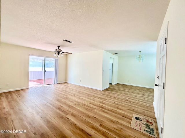 unfurnished room featuring a textured ceiling, light hardwood / wood-style flooring, and ceiling fan with notable chandelier