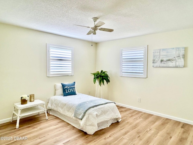 bedroom with ceiling fan, light hardwood / wood-style flooring, and a textured ceiling