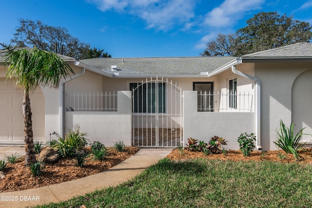 view of front of house featuring a garage, a fenced front yard, roof with shingles, a gate, and stucco siding