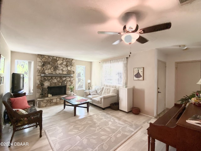 living room featuring ceiling fan, light hardwood / wood-style floors, and a fireplace