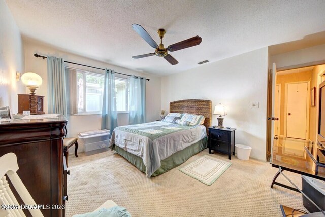 bedroom with a textured ceiling, light colored carpet, and ceiling fan