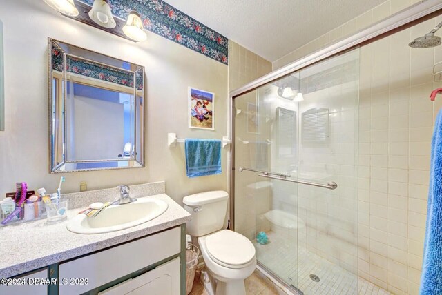 bathroom with an enclosed shower, vanity, a textured ceiling, and toilet