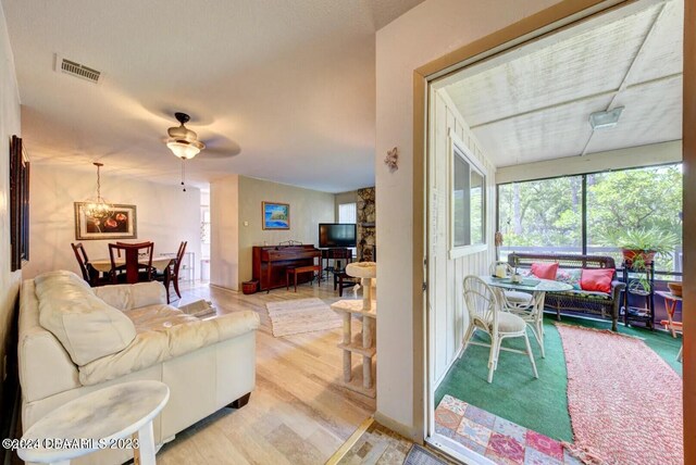 living room with hardwood / wood-style floors and ceiling fan with notable chandelier