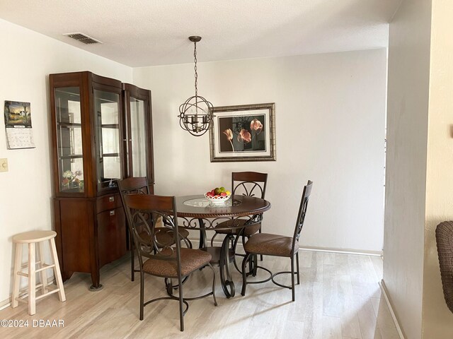 dining space featuring light hardwood / wood-style floors, a chandelier, and a textured ceiling