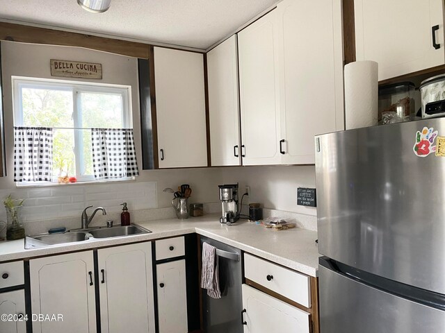 kitchen featuring white cabinets, decorative backsplash, a textured ceiling, sink, and appliances with stainless steel finishes