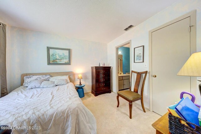 bedroom featuring ensuite bath and light carpet