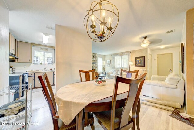 dining space featuring light hardwood / wood-style floors and ceiling fan with notable chandelier