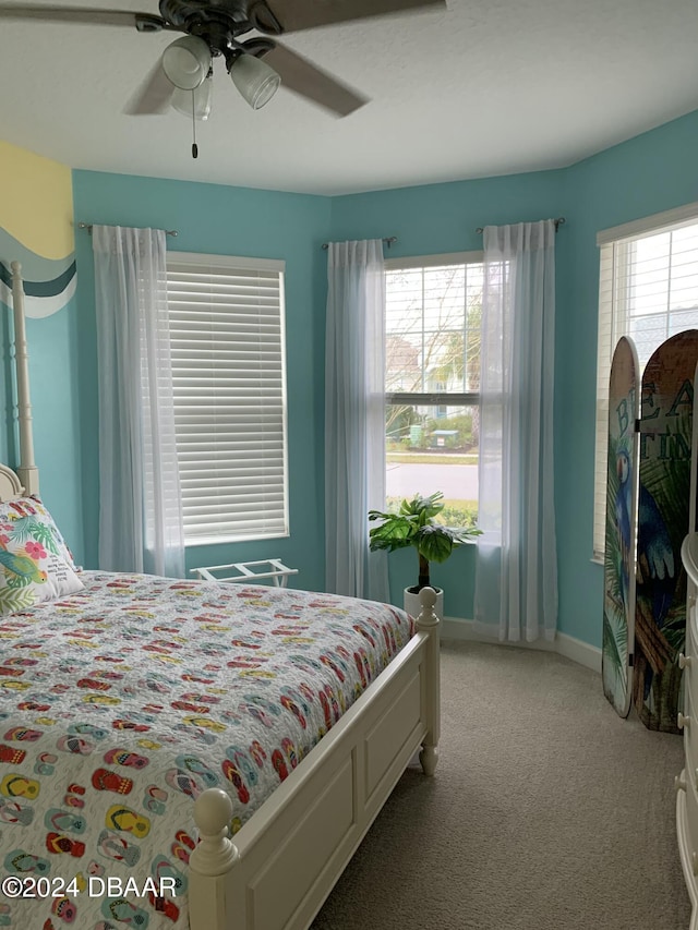 carpeted bedroom featuring multiple windows and ceiling fan