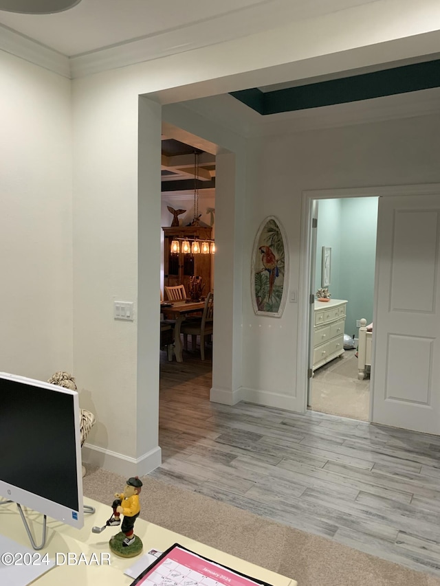 hall featuring light wood-type flooring, crown molding, and an inviting chandelier