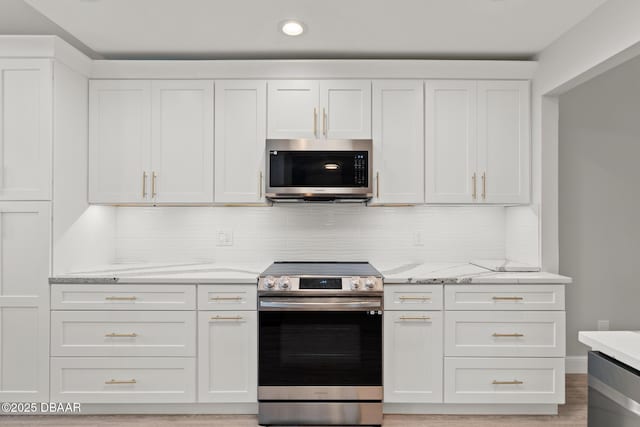 kitchen with white cabinets, decorative backsplash, light stone counters, and appliances with stainless steel finishes