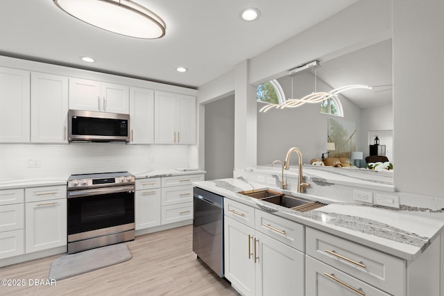 kitchen with backsplash, sink, light stone countertops, white cabinetry, and stainless steel appliances