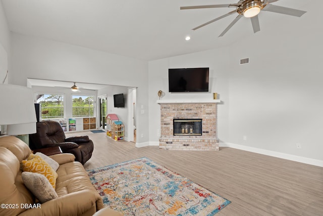 living room with hardwood / wood-style floors, ceiling fan, vaulted ceiling, and a brick fireplace